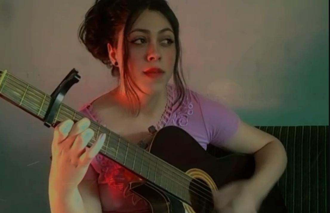 Renata Pattez tocando violão com luz colorida